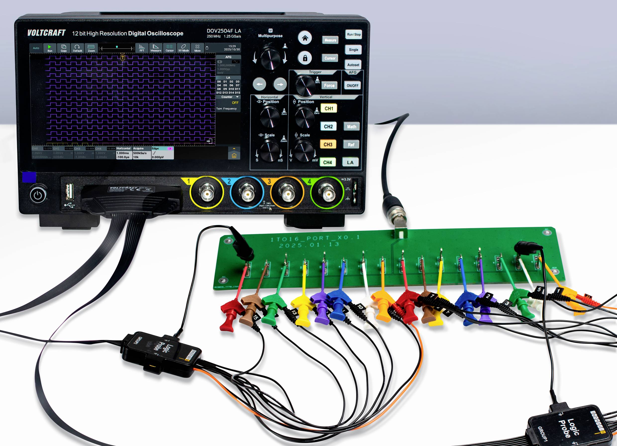 An oscilloscope displaying a waveform is connected to a green circuit board with multiple colored clips attached to it.