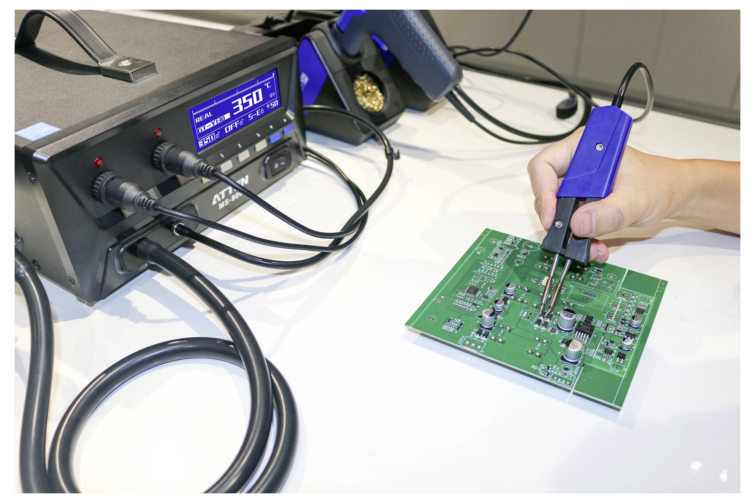 A person uses a soldering iron to repair a green circuit board. A digital soldering station displays a temperature of 350°C.