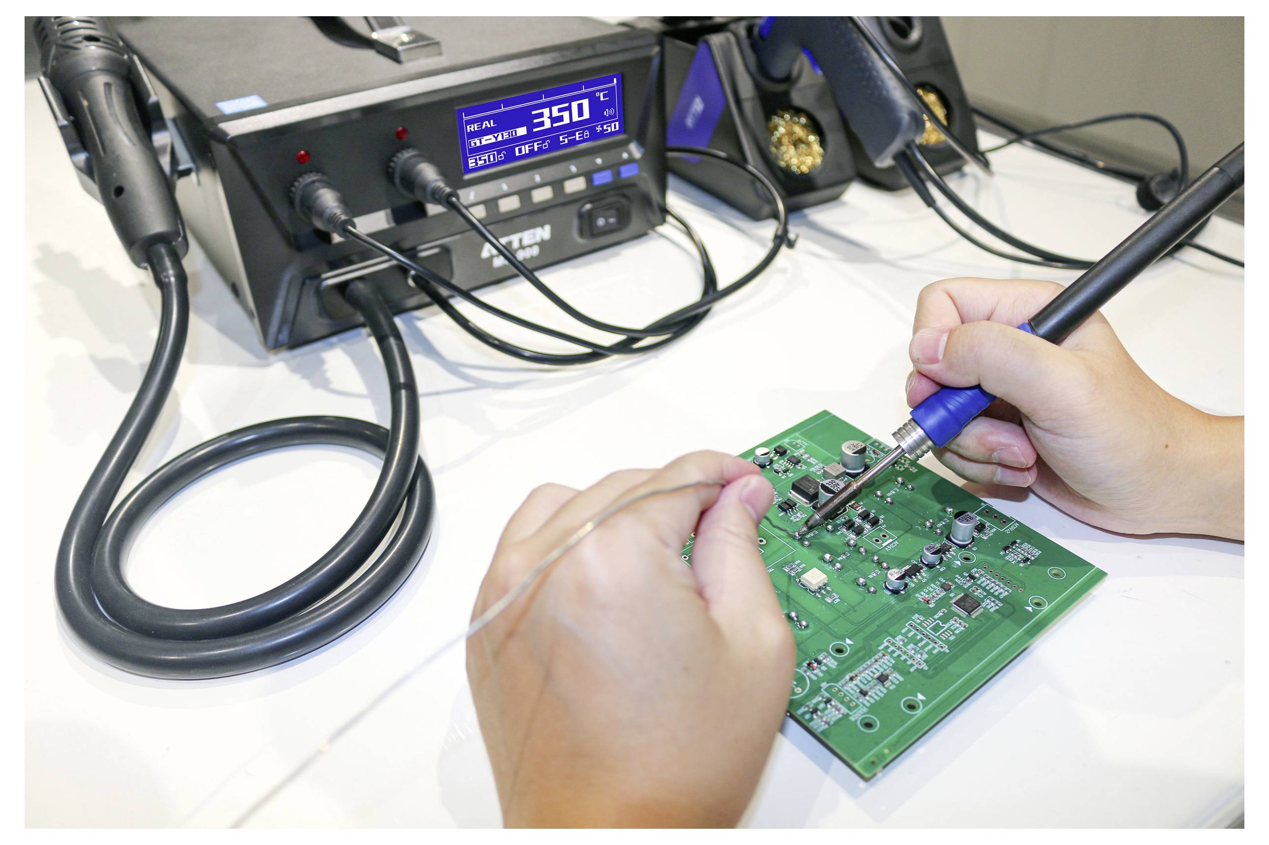 A person is soldering a green electronic circuit board with a soldering iron. A digital soldering station displays a temperature of 350°C.