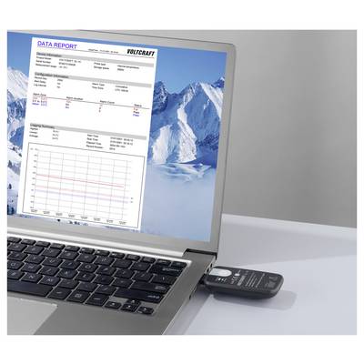 Laptop displaying a VOLTCRAFT 'DATA REPORT' with alarm summary and line graph, alongside a snowy mountain wallpaper; a USB device is plugged in.