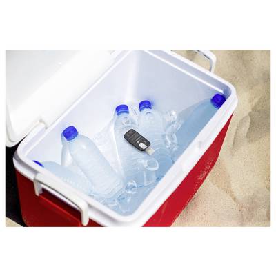 A red cooler on sand contains several plastic water bottles and a car key, highlighting a beach day setup.