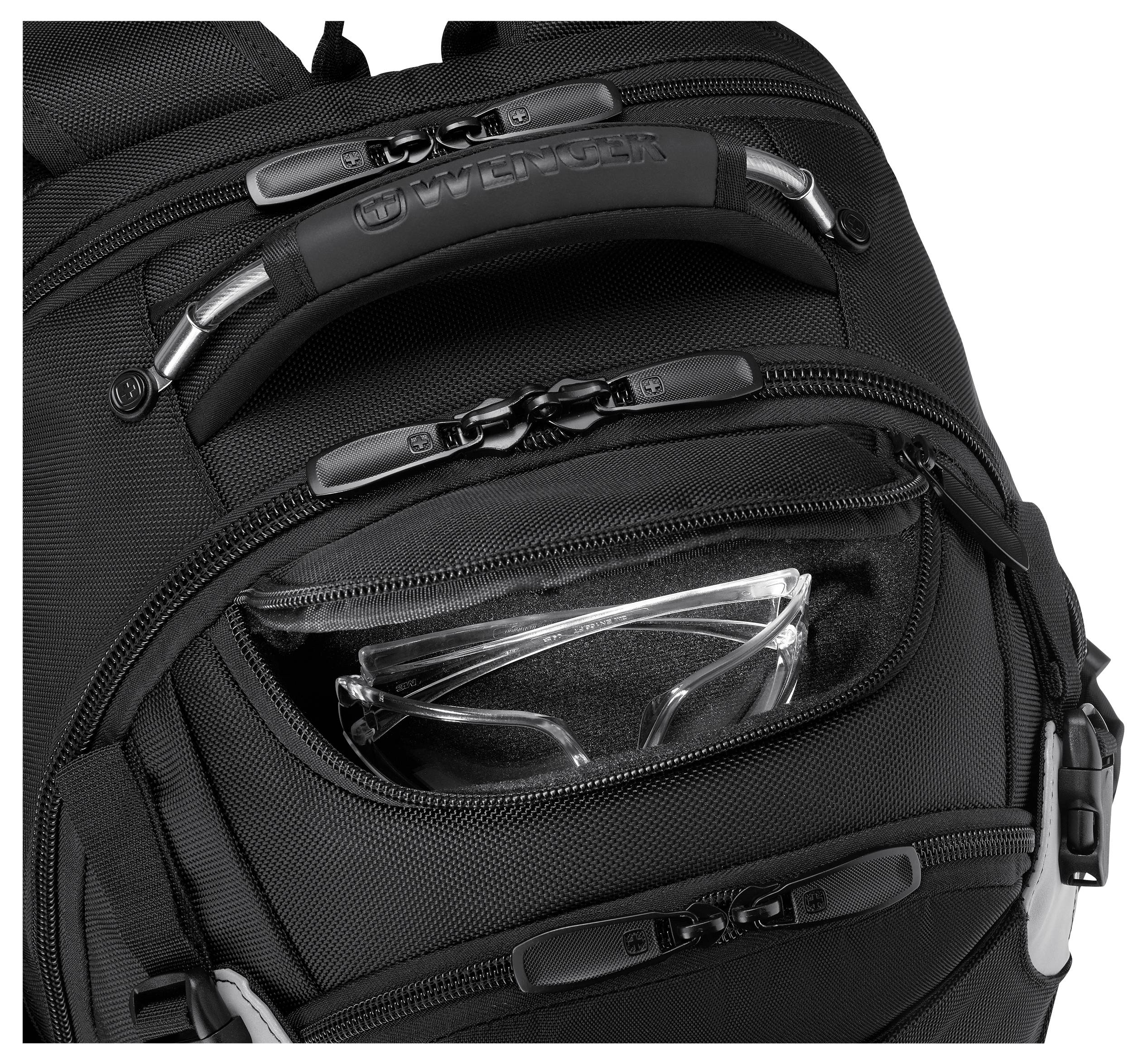 A black backpack with a top handle, multiple zippered compartments, and a front pocket containing a pair of clear safety glasses.