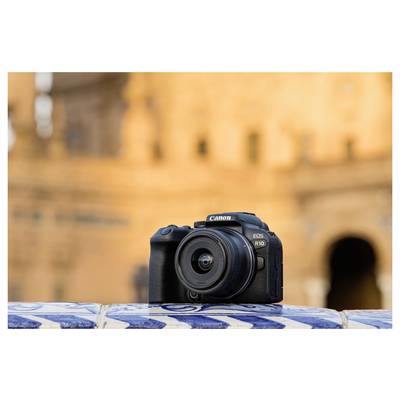 A Canon EOS R10 camera resting on a tiled ledge with blurred historic architecture in the background.