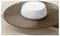 A white, round wireless router with a simple design sits on a wooden table, featuring a small green indicator light in front.