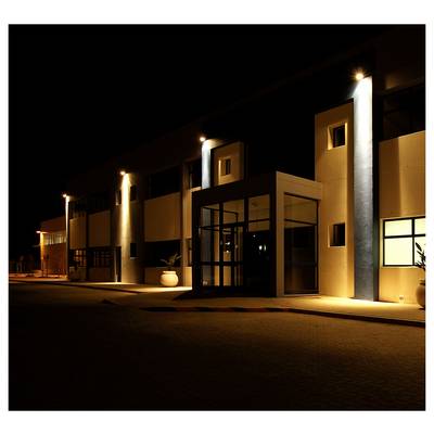 A modern building entrance lit at night, with exterior lights illuminating the facade.