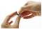 Two hands folding a small piece of dark material against a plain white background.