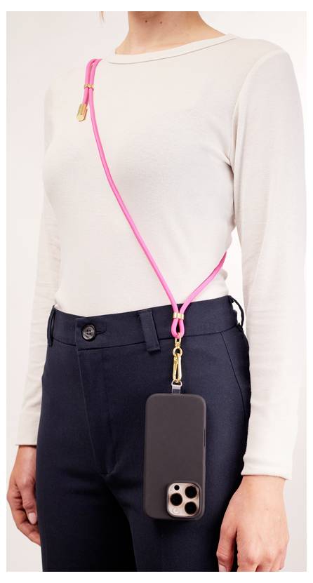 A person wearing a white long-sleeve top and dark pants is shown with a pink strap connected to a black smartphone case, worn over the shoulder.