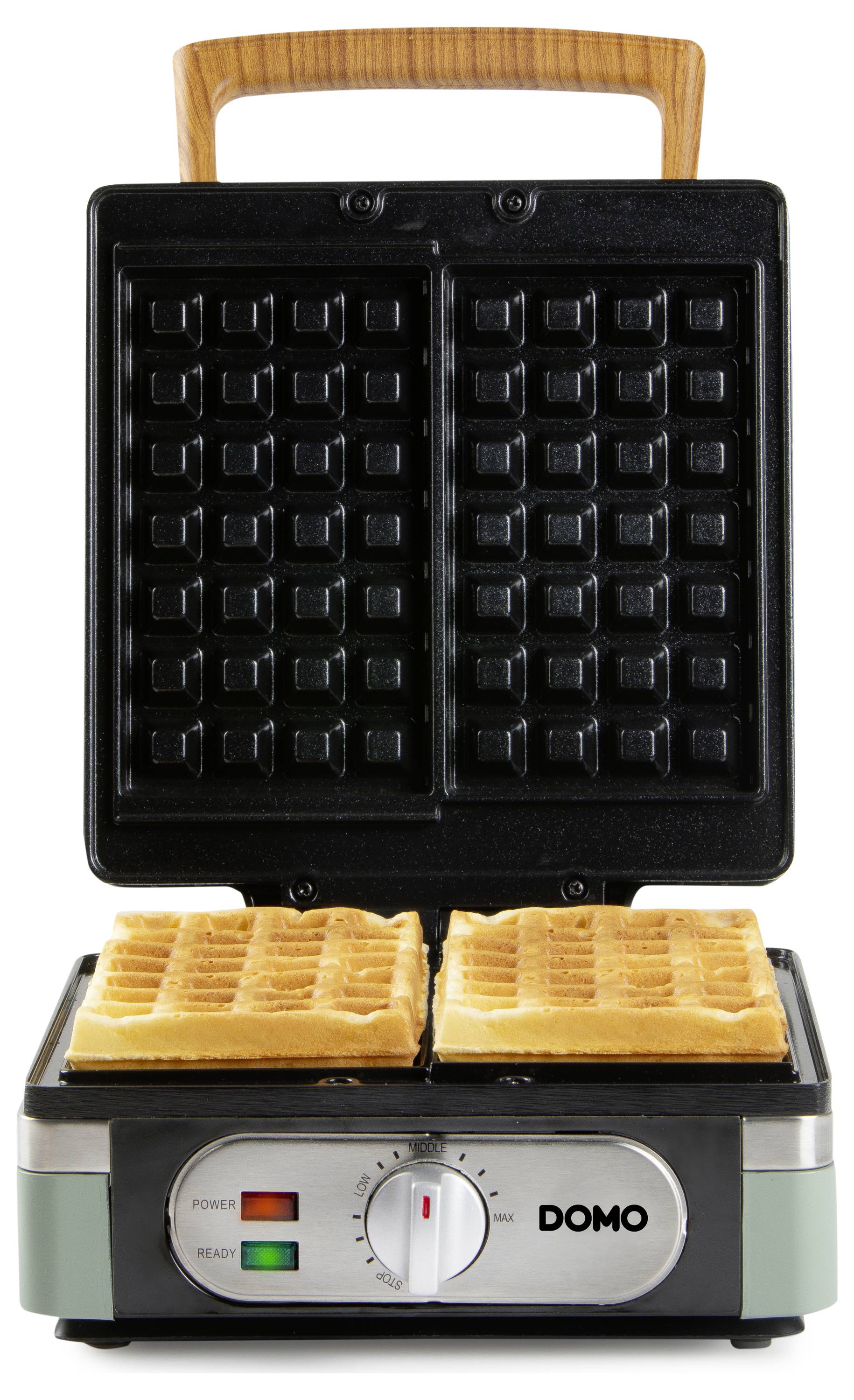 Waffle maker with an open lid showing two cooked waffles inside. The machine has a dial and indicator lights for power and readiness.