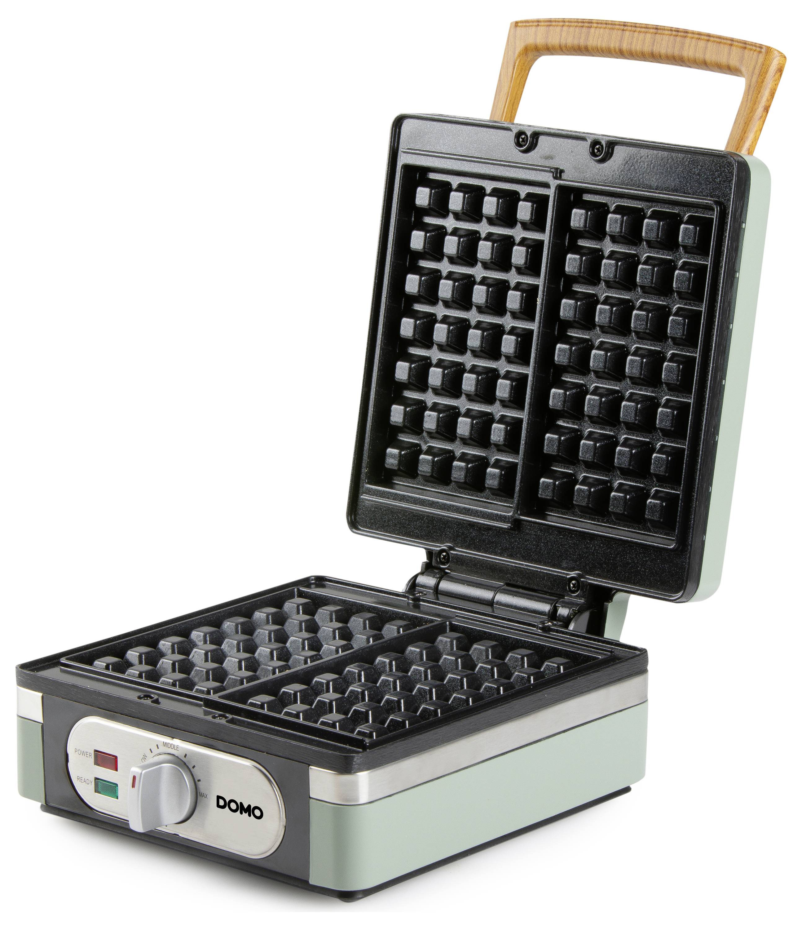 A green waffle maker with wooden handle, open to reveal two waffle plates. The control knob and indicator lights are on the front panel.