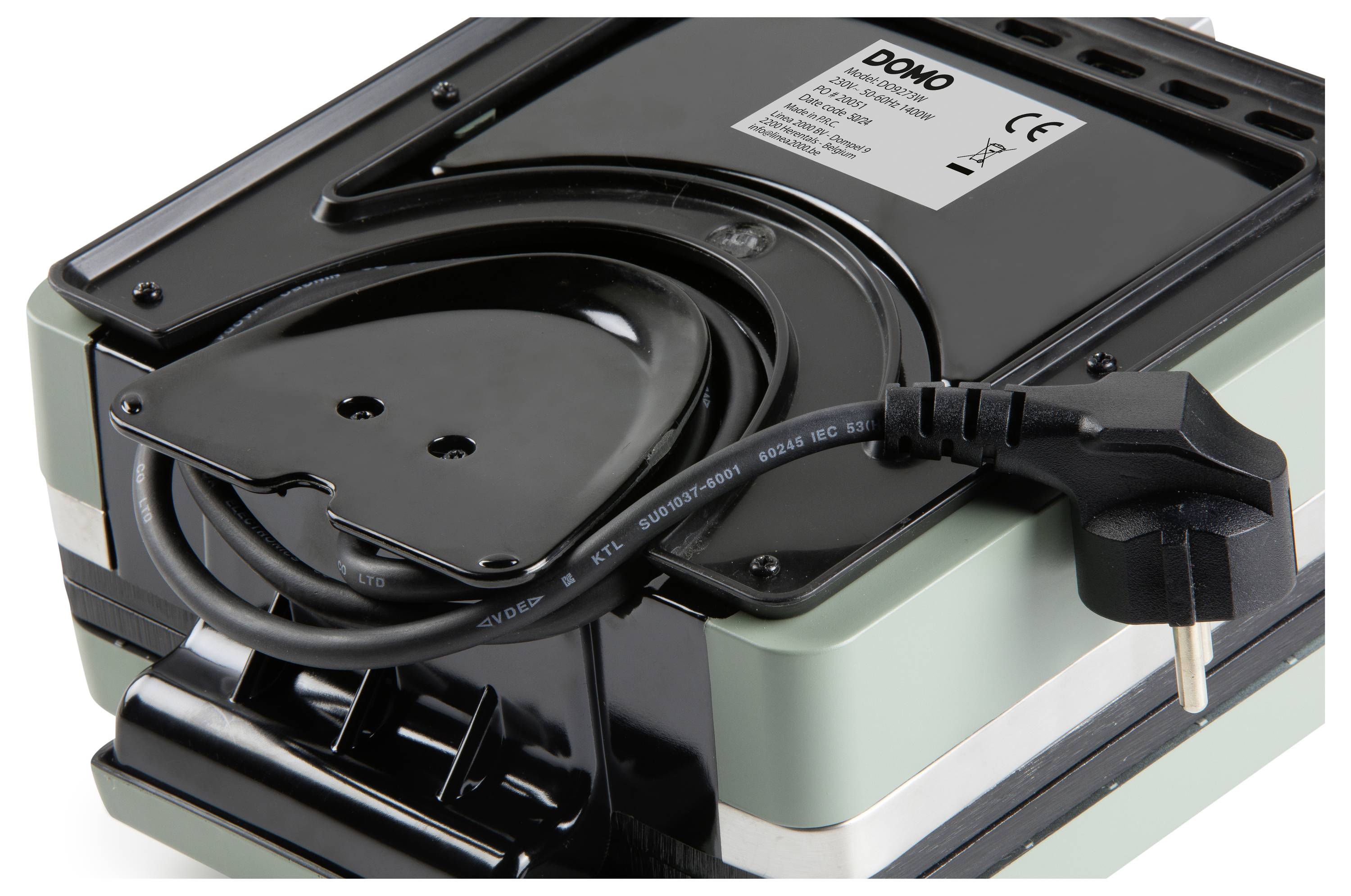 A close-up of a waffle maker showing the underside with a coiled power cord and plug, labeled with 'Dono' and product specifications.