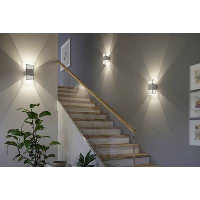 A modern staircase with wooden steps and a railing, illuminated by three wall-mounted lights. Decorative framed artwork and a plant add aesthetic appeal.