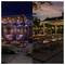 Outdoor patio divided by time: starry night with purple lights on left, sunset with warm lights on right. Cozy seating and decor.