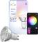 A Philips Hue Essential smart bulb next to its packaging and a smartphone showing a color selection app interface.