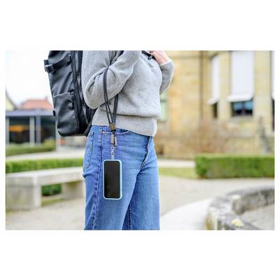 A person outdoors wearing a gray sweater and jeans, carrying a black backpack. A smartphone is attached to their belt with a strap.