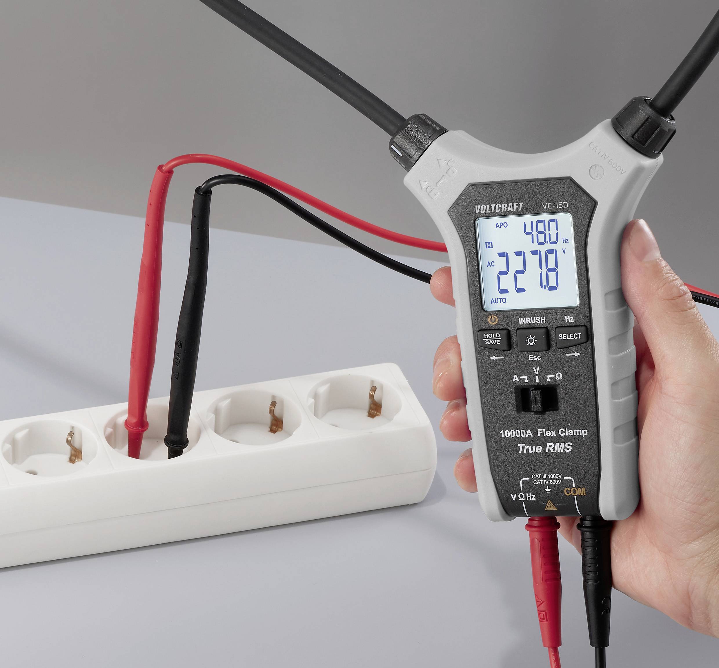 A digital clamp meter shows readings of 48.0 and 227.8, connected to a power strip with red and black probes for measuring voltage.