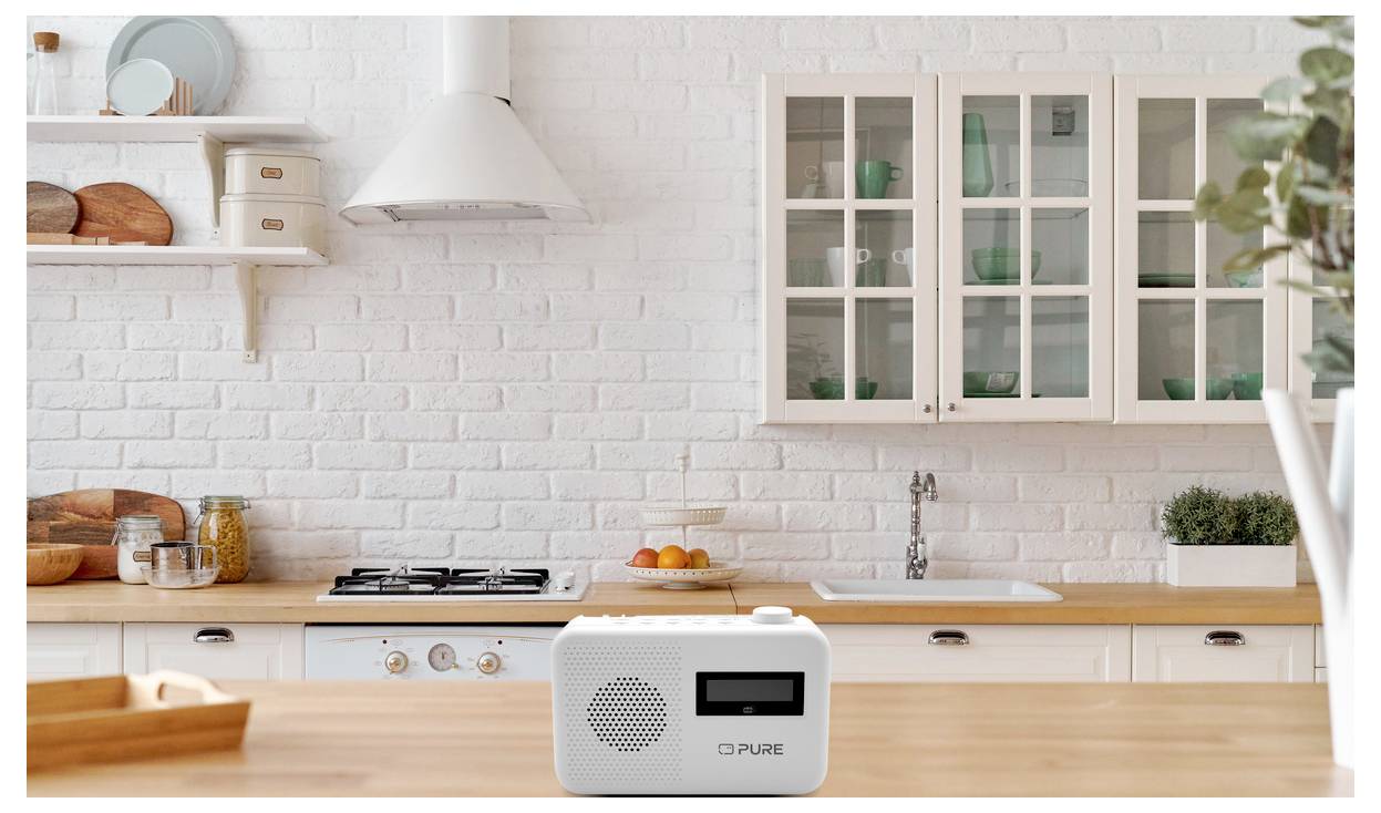 A modern kitchen features white cabinets and a wooden countertop with a small white radio prominently placed on the counter.