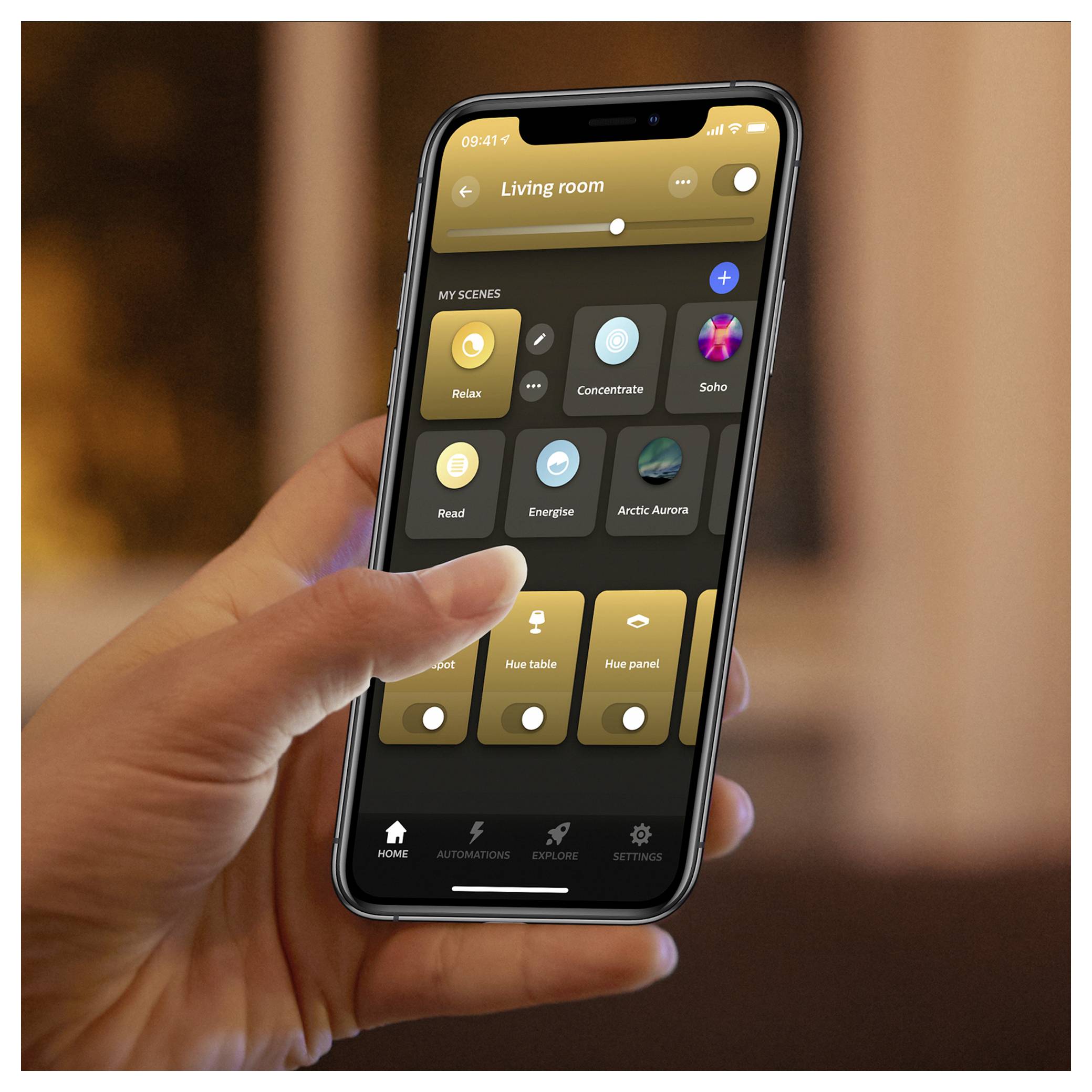 Person holding a smartphone showing a smart home app interface with various lighting presets for the living room, such as 'Relax' and 'Concentrate'.