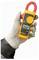 A hand wearing a protective glove holds a digital clamp meter, showing a reading of '200.0'. The device is used for measuring electrical current.