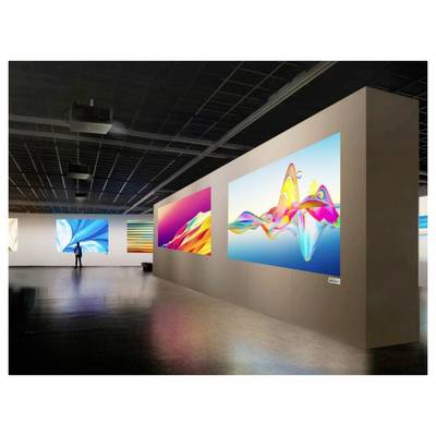 An art gallery displaying large, colorful abstract digital artworks on the walls. A person stands viewing one of the pieces.