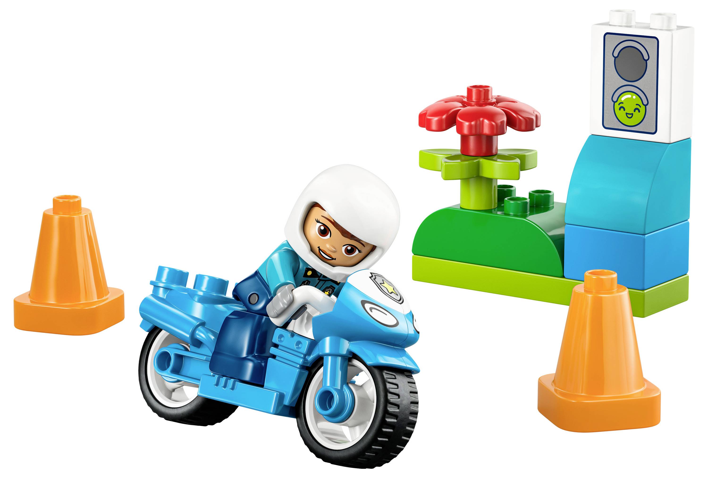A toy figure on a blue motorcycle among two orange cones and a colorful building block structure with a red flower and a control panel.