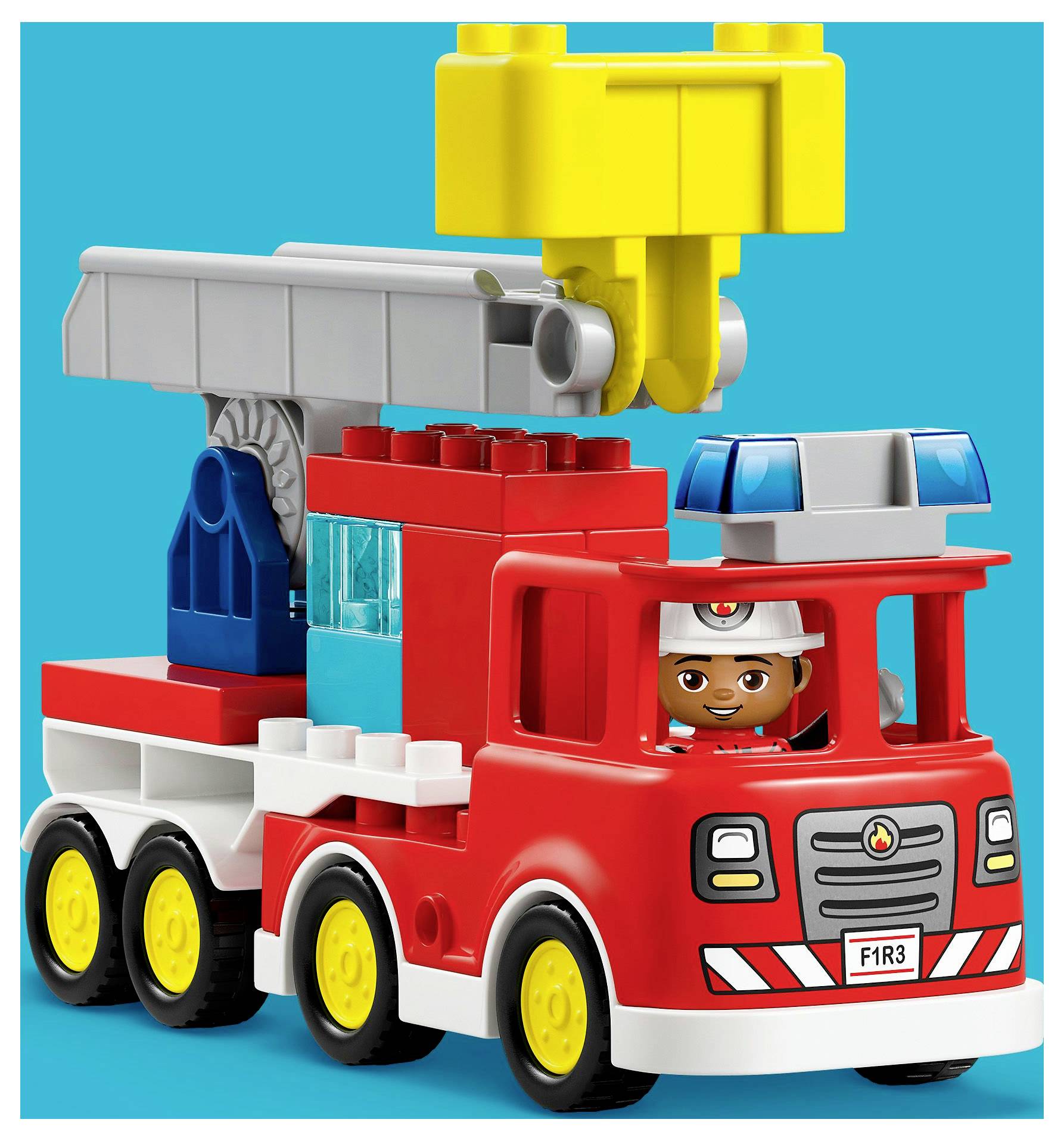 A children's toy fire truck made of building blocks, featuring a red truck with a smiling figure in a firefighter helmet in the driver's seat.