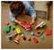 A child plays on a wooden surface with a red toy fire truck and various colorful toy blocks and figures scattered around.