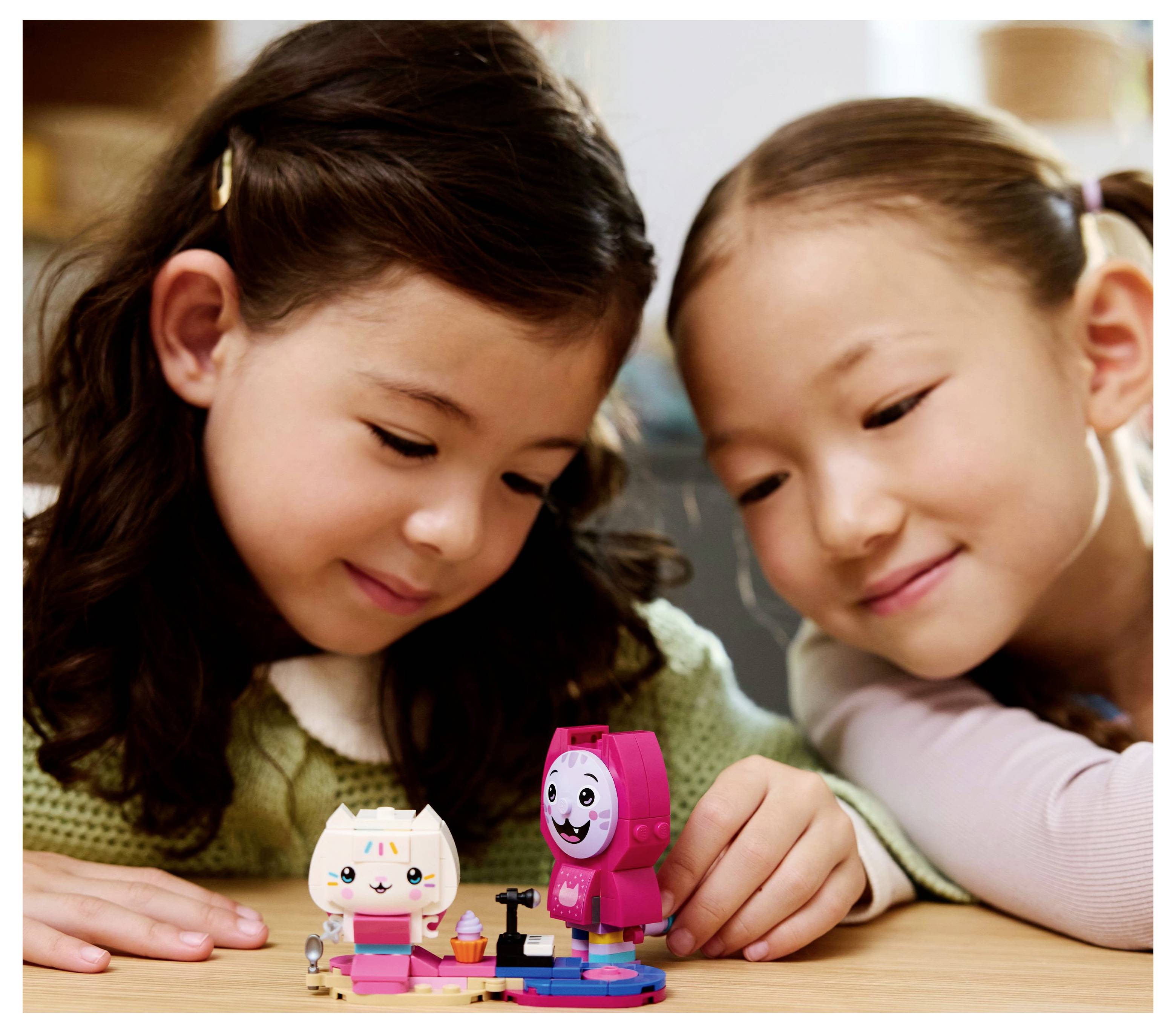 Two young children engage in imaginative play with colorful, small toy figures on a table, focusing intently on their activity.