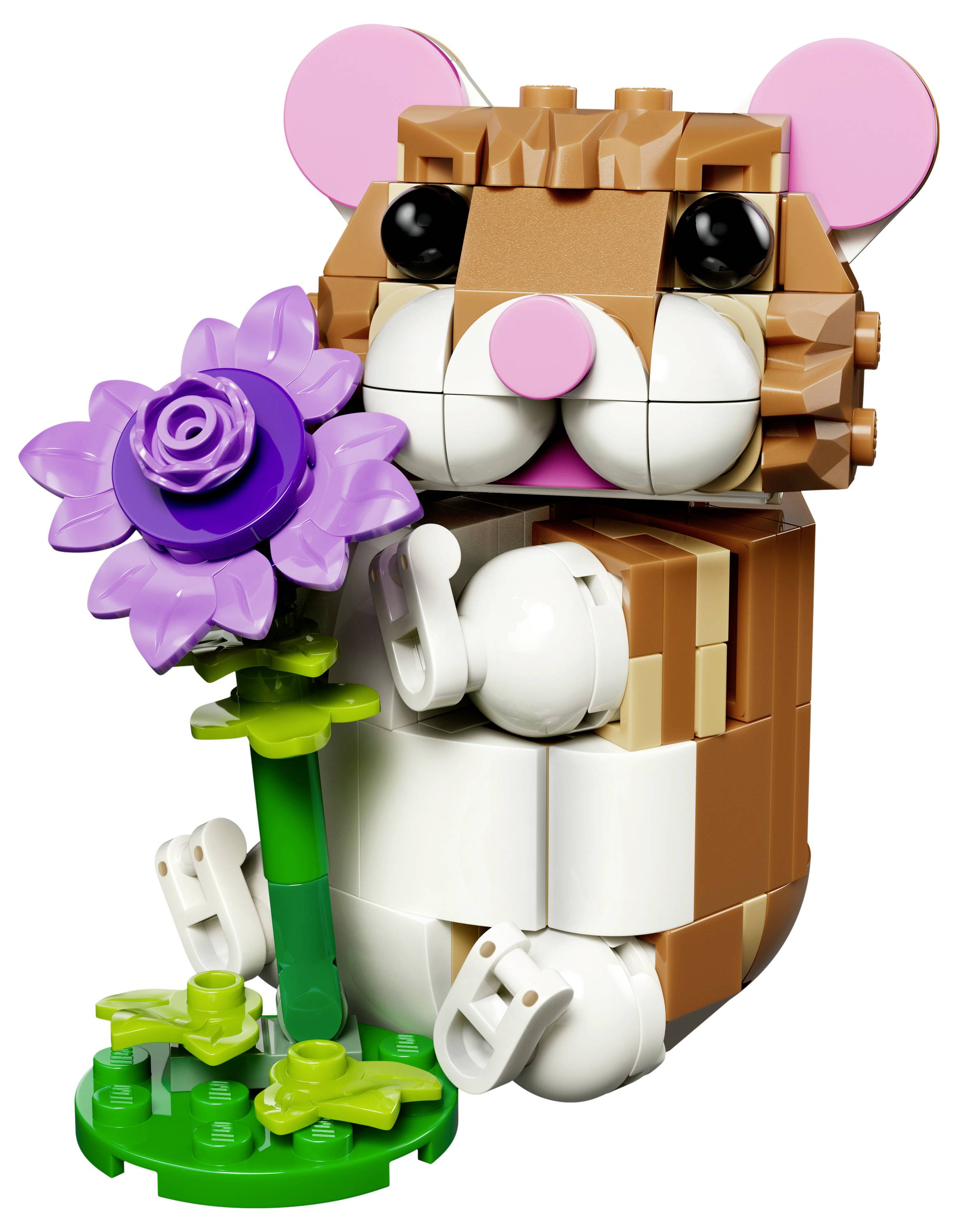 A toy hamster made of interlocking bricks holds a purple flower and stands on a small green base.