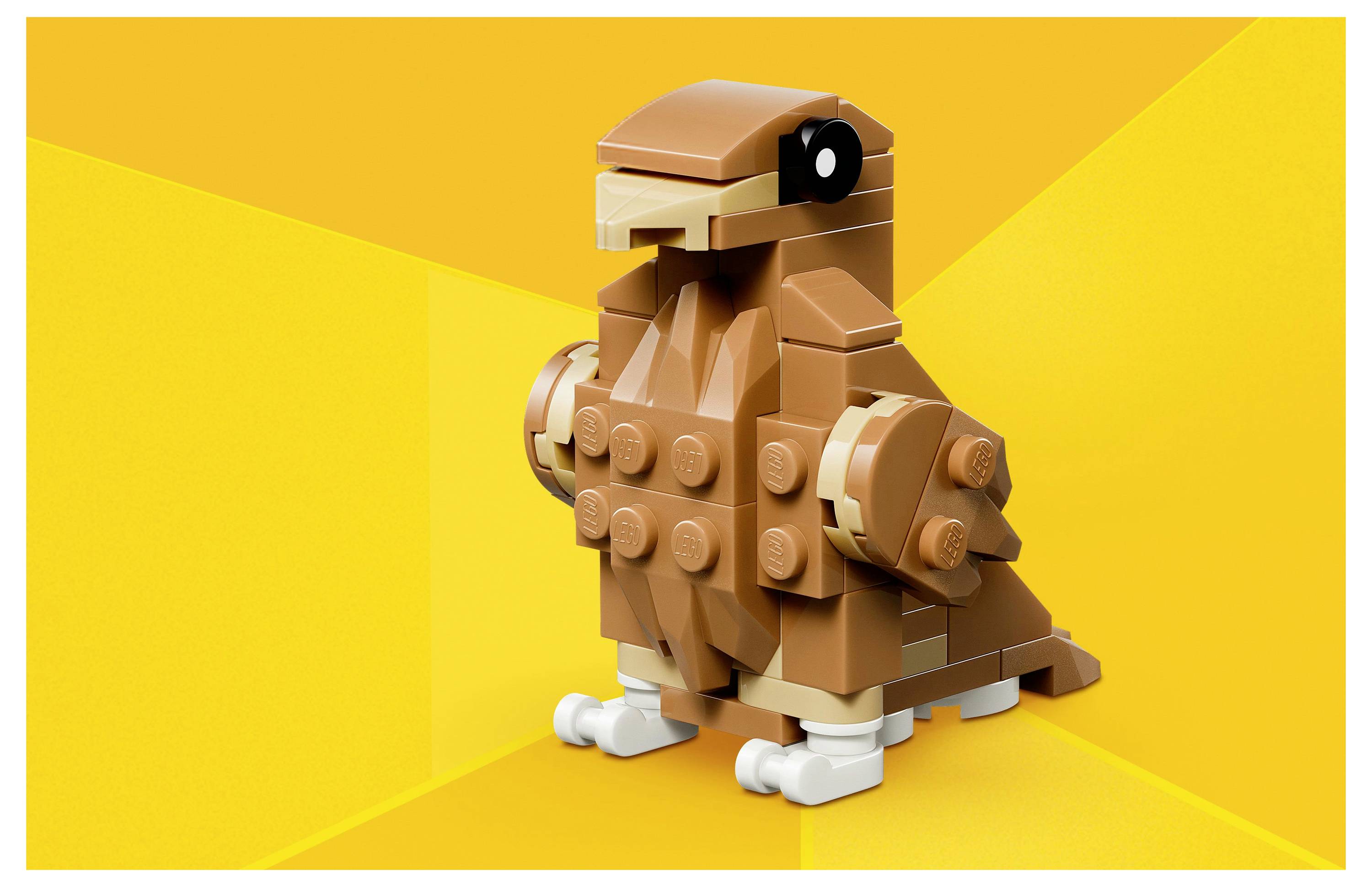 A small brown block construction resembling a bird, made from toy building bricks, set against a bright yellow geometric background.