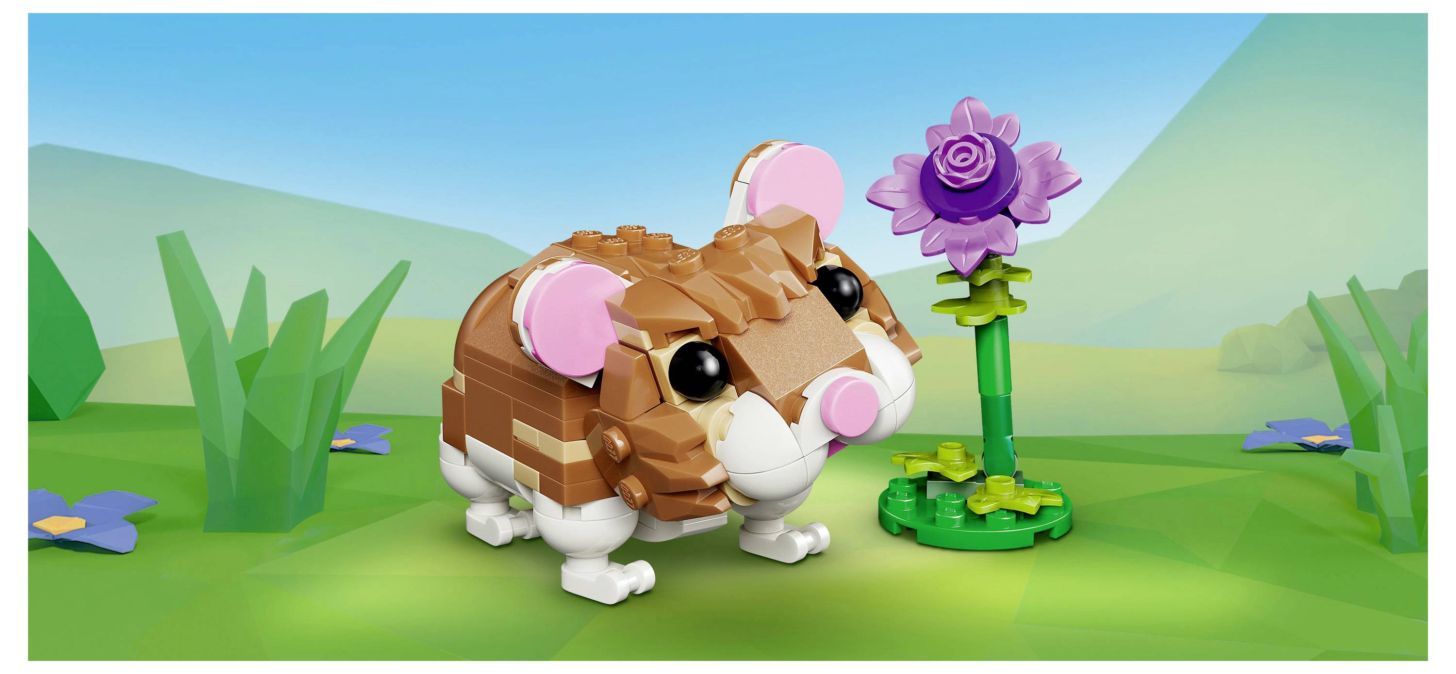 A small LEGO hamster stands on green grass with a purple flower beside it. The background features a grassy landscape under a blue sky.