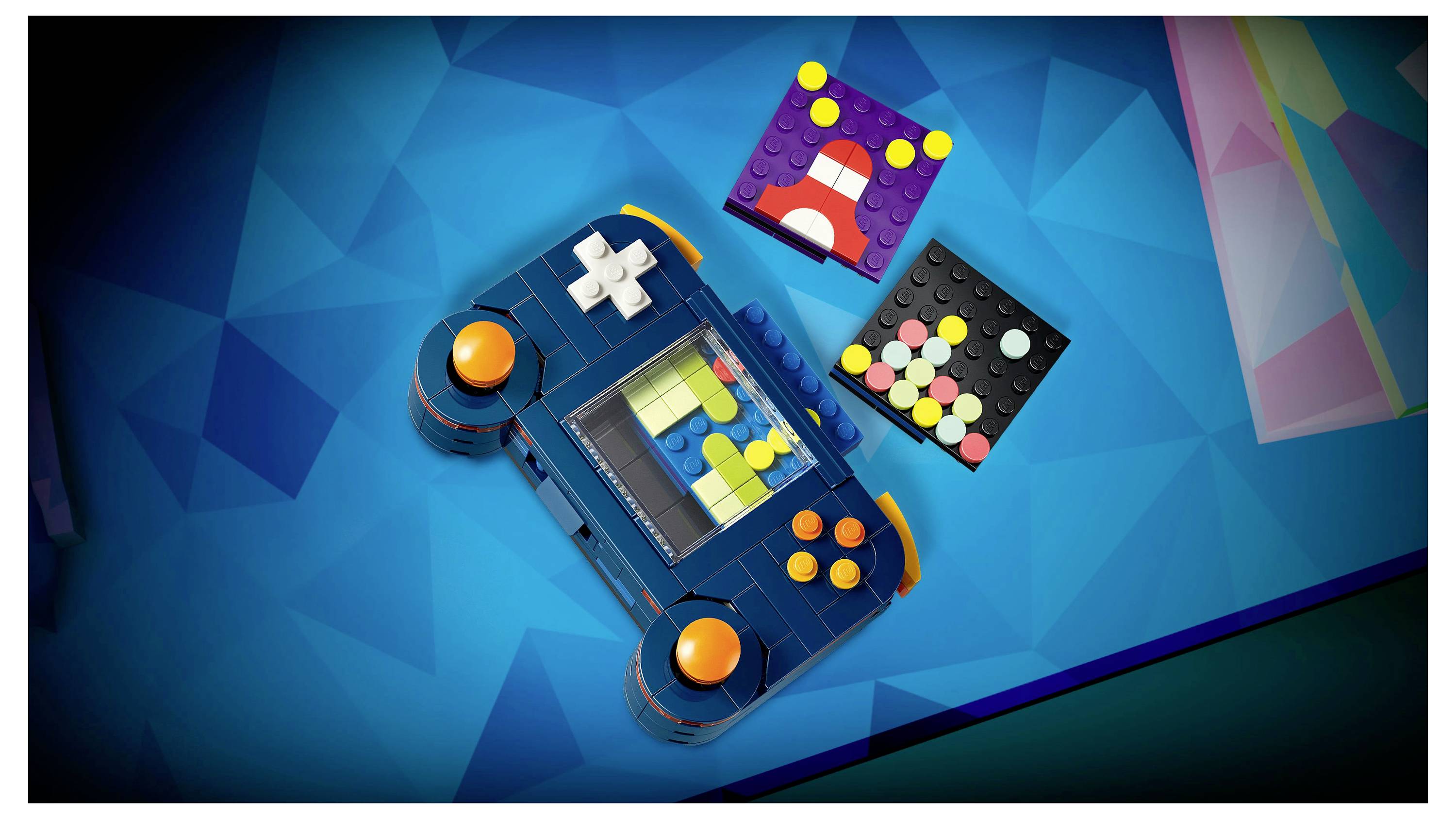 A colorful game controller and two square LEGO-like building blocks with abstract designs, set against a geometric blue background.