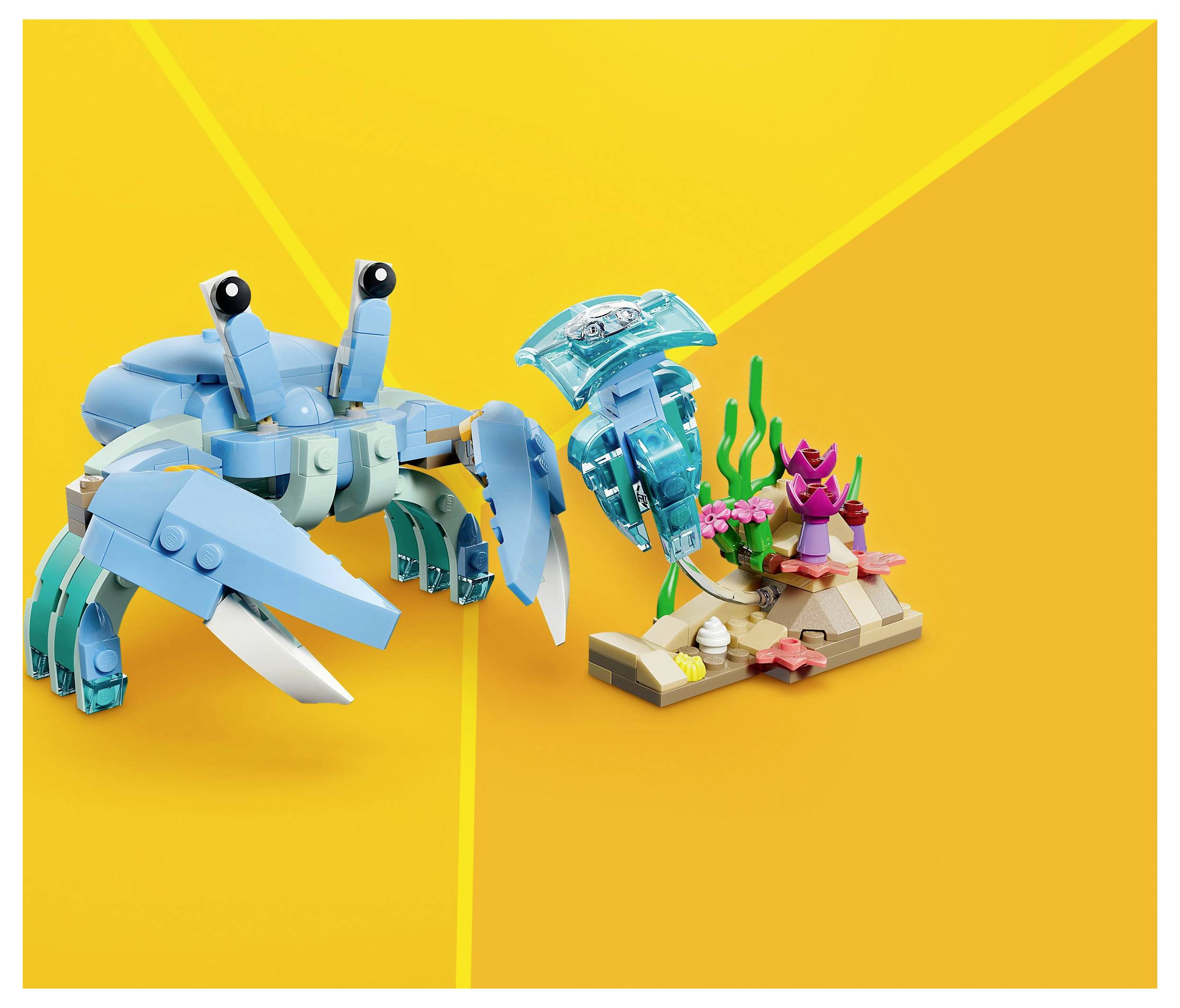 A blue crab and lobster made of building blocks stand on a small ocean-themed base with coral and seaweed on an orange background.