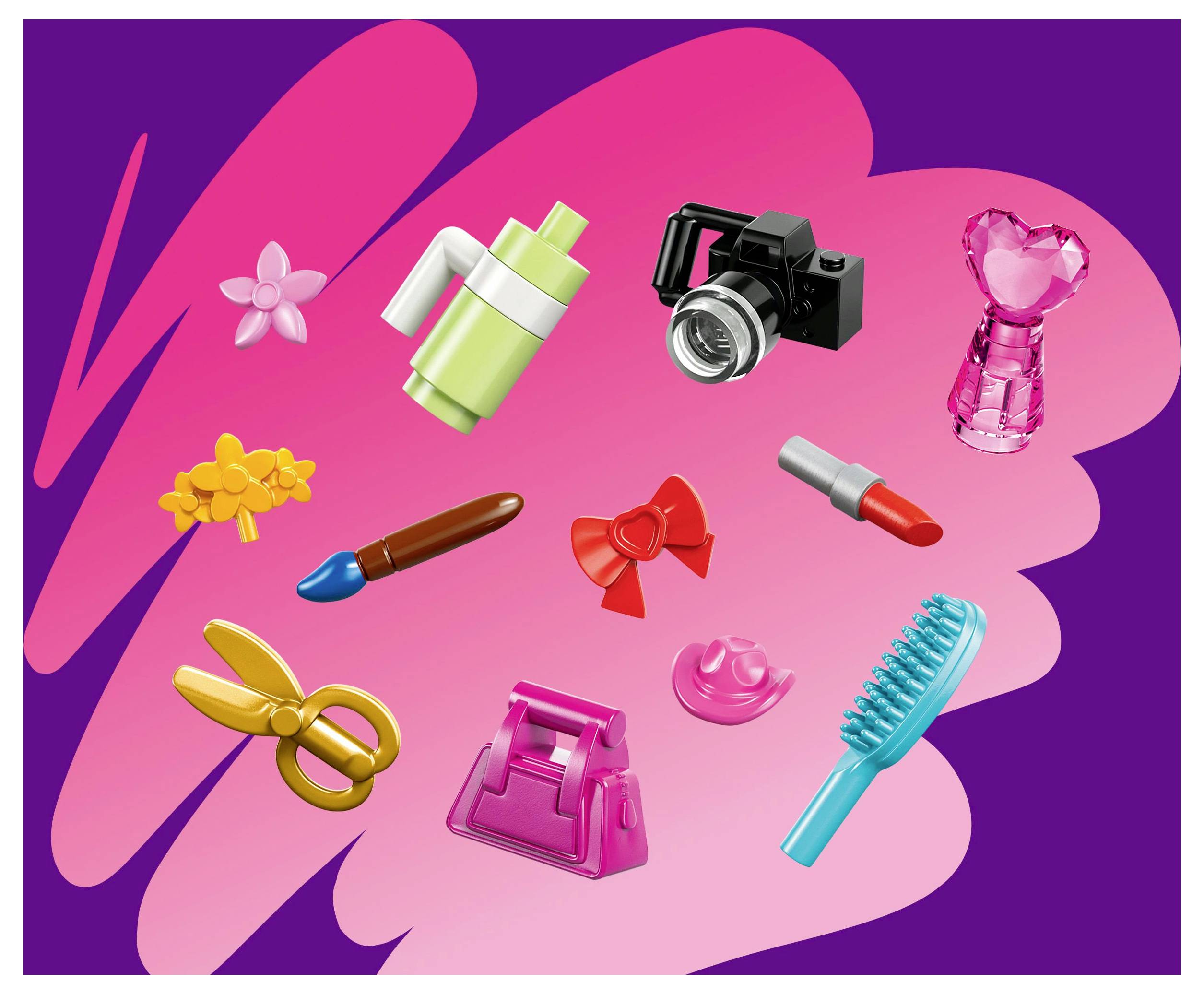 Various colorful toy-like objects, including a camera, scissors, a lipstick, and a brush, are scattered on a pink and purple background.