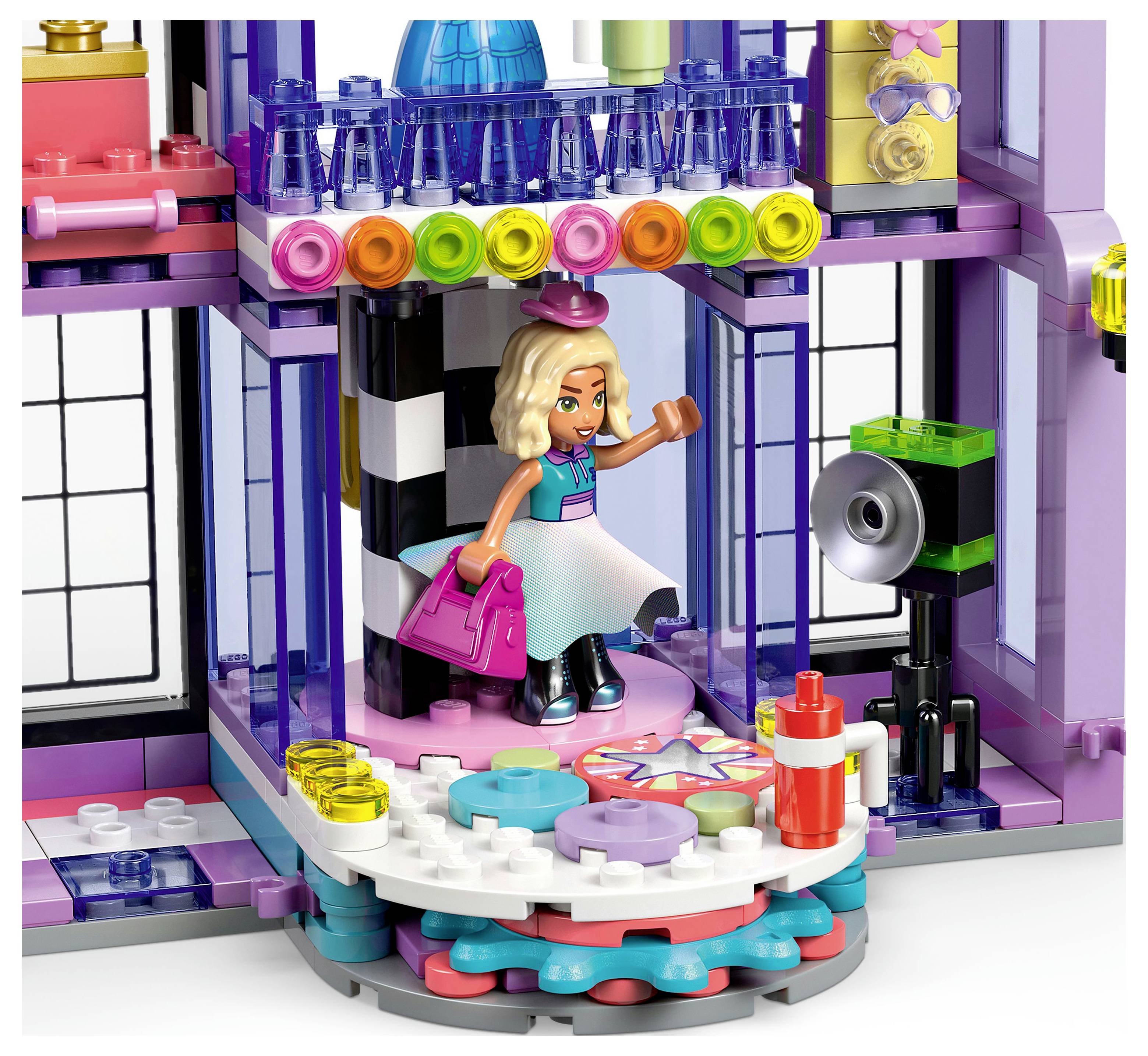 A toy fashion studio set with a mannequin, camera setup, and accessories like a handbag, depicting a vibrant fashion scene.