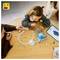 A child and adult collaborate to build a LEGO set on a table, with a tablet displaying instructions nearby.