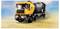 A yellow and black toy cement mixer truck on a sandy surface with a clear sky background.