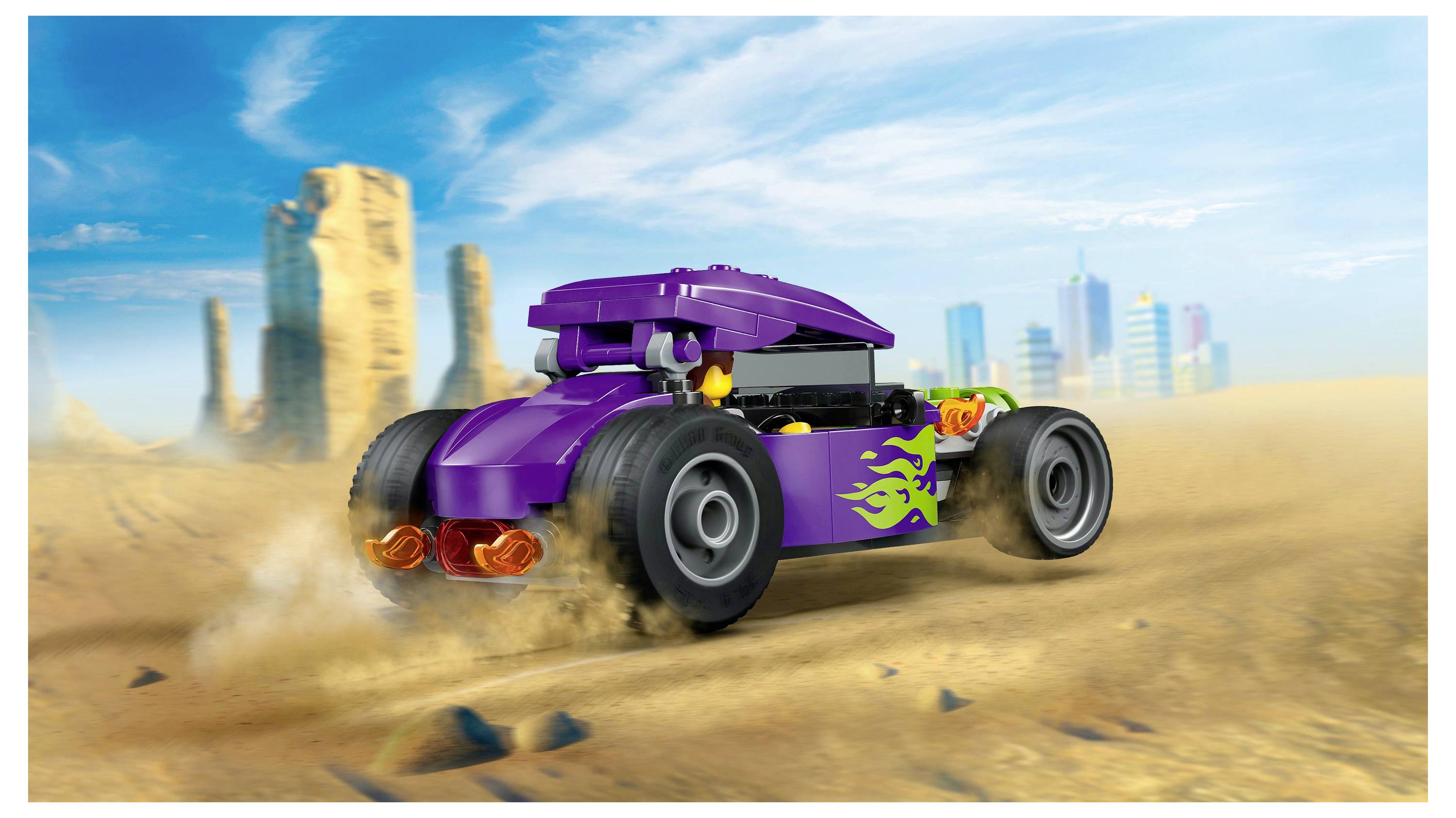 A purple toy car speeds through a desert landscape, kicking up sand. Tall rock formations and distant city skyscrapers are visible in the background.