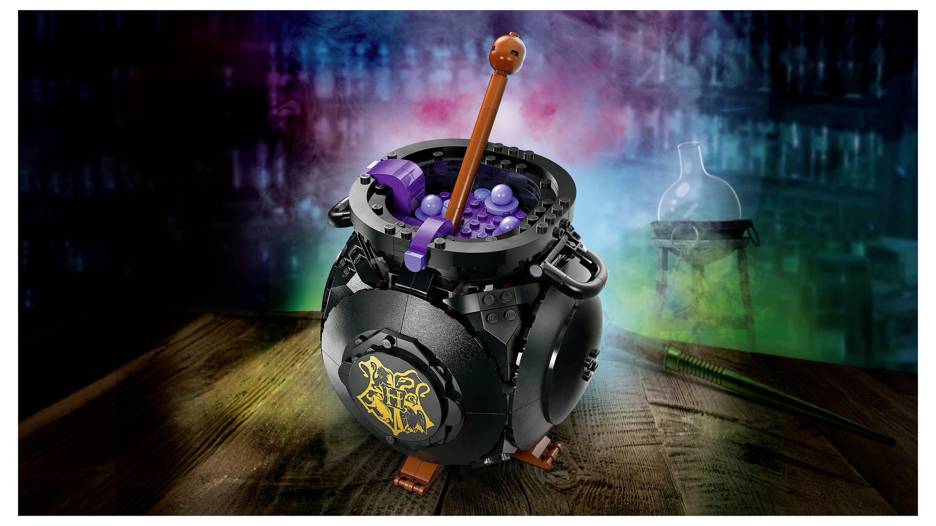 A black cauldron toy with a glowing potion, featuring a stirring stick and purple bubbles, set on a wooden table against a misty background.