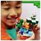 A child holding a LEGO Minecraft set featuring iconic characters and elements like a tree, fox, Creeper, and TNT block, smiling with excitement.