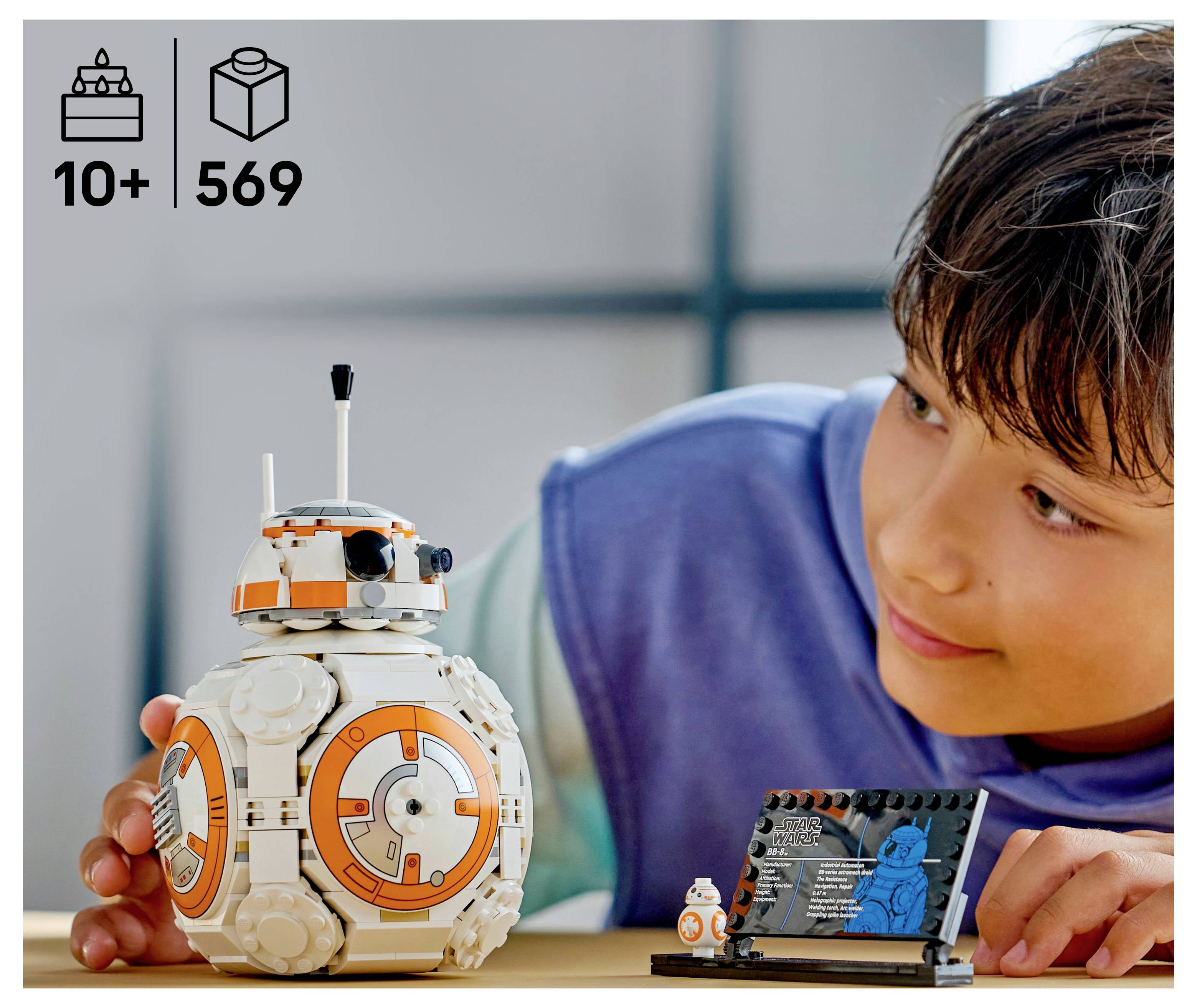 A child is looking at a LEGO model of a droid. The set has '10+' and '569' pieces indicated.