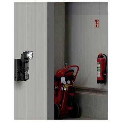 A flashlight mounted on a wall illuminates a fire safety area with a hanging fire extinguisher and a mobile fire cart nearby.
