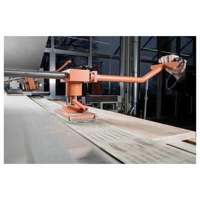 A person operates a machine to bend a metal sheet in an industrial setting, highlighting precision in metal fabrication processes.