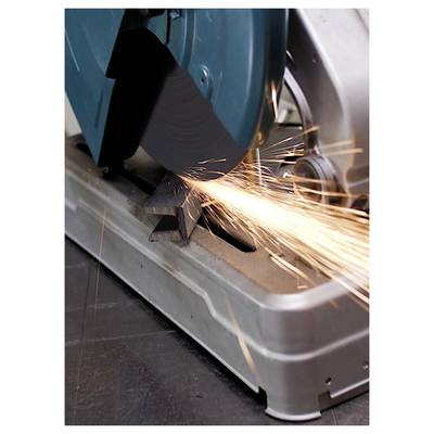 A metal cutting saw with blue circular blade in motion, producing bright orange sparks as it cuts through a metal bar on a workshop floor.