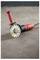 A red and black angle grinder with a sharp disc, resting on a concrete floor, used for cutting or grinding tasks.
