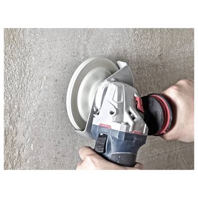 A person using a handheld angle grinder with a circular blade on a concrete surface, focused on smoothing or cutting the material.