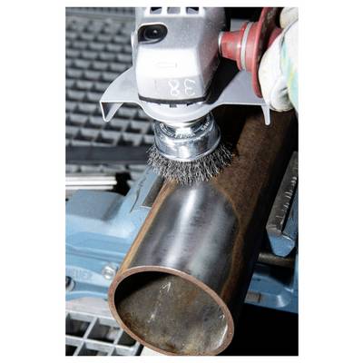 A wire brush tool is used to clean rust from a metal pipe, clamped on a workbench, indicating metal surface preparation.