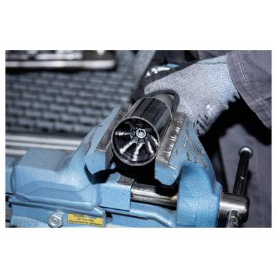 A person wearing gray gloves uses a blue metal vise to secure a cylindrical metal part with a shiny, star-shaped interior.