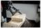 A reciprocating saw cutting through a piece of wood, with wood shavings flying around. The focus is on the blade and the cut.