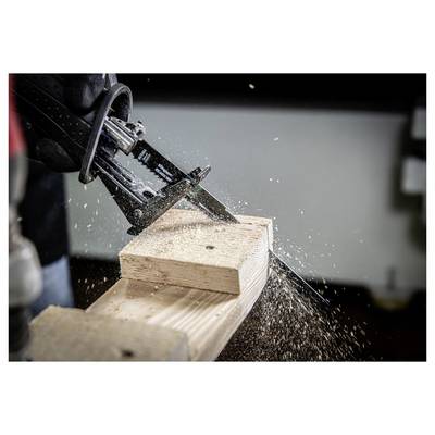A jigsaw in action, cutting through a wooden plank. Sawdust scatters around the workbench, indicating the progress of the cut.