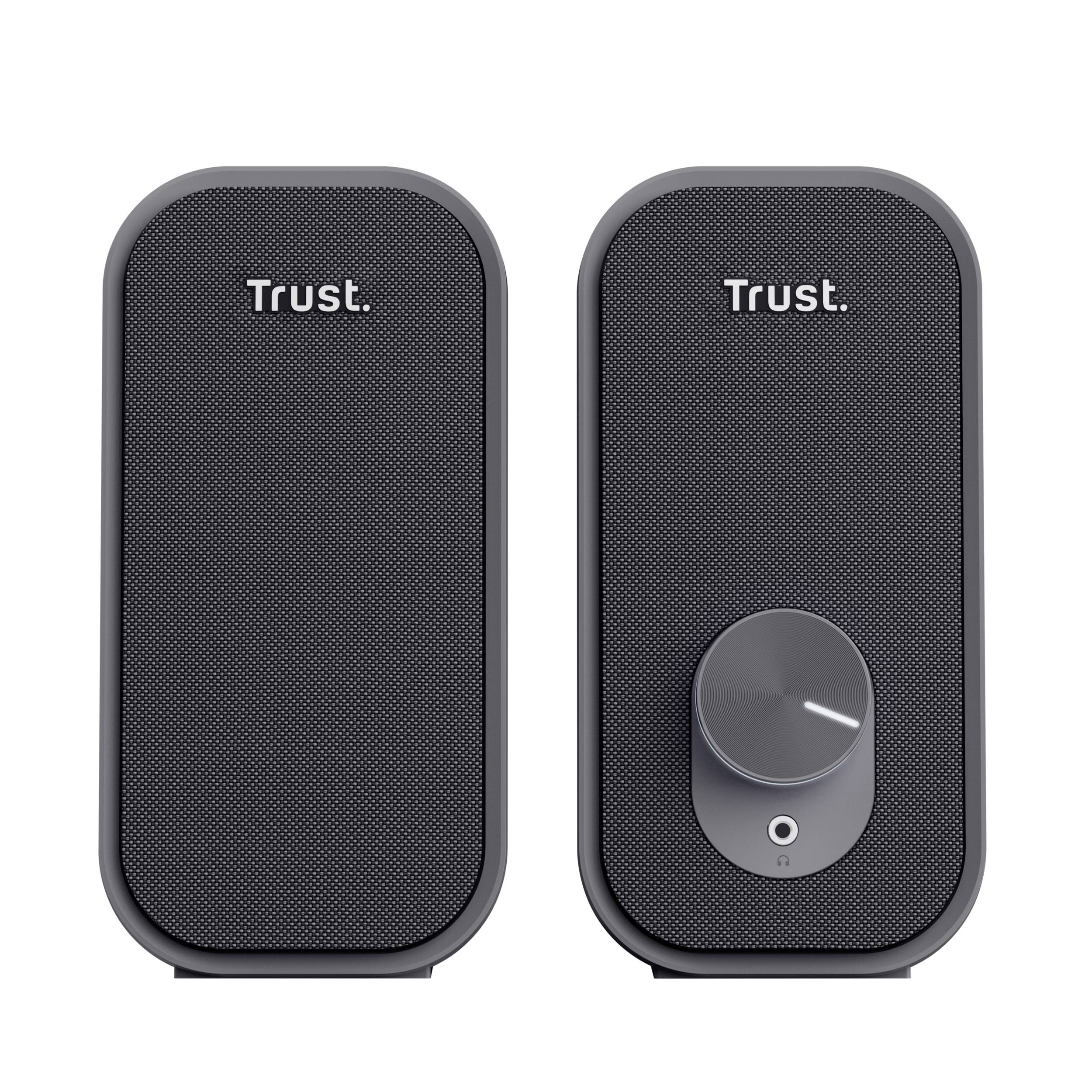 Two black Trust computer speakers. The left speaker features branding, while the right speaker includes a volume control dial.